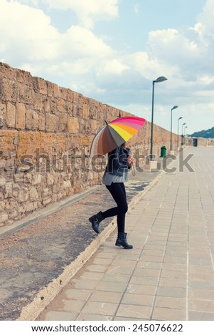 girl holding a big umbrella with color stripes