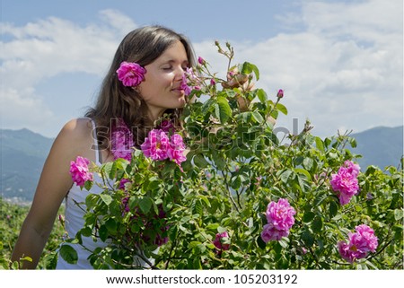 Beautiful girl smelling a rose in a field of roses