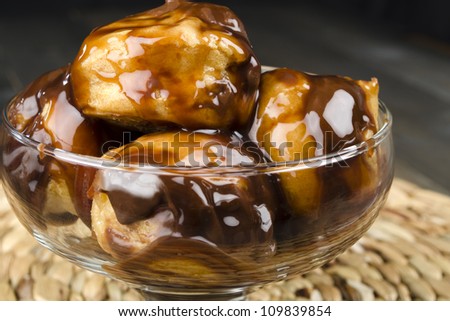 Profiteroles with chocolate sauce and chocolate syrup in a glass bowl. Close up