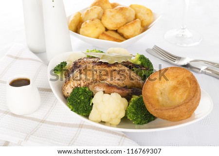 Roast Dinner - Roast partridge served with cauliflower, broccoli, roast potatoes, Yorkshire pudding and a jug of gravy. Traditional British Sunday and Christmas meal.