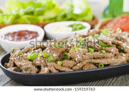 Bulgogi - Korean grilled marinated beef served with green chillies, garlic, ssamjang, kimchi and lettuce leaves.