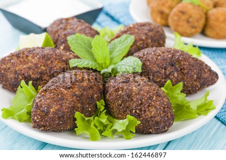 Kibbeh - Middle Eastern minced meat and bulghur wheat fried snack. Also popular party dish in Brazil (kibe). Falafel and tzatziki dip on background.