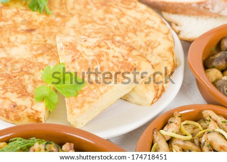 Spanish Tortilla - Traditional Spanish omelette made with potatoes and fried in olive oil. Various other tapas on the table.