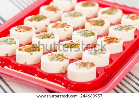 Cheese Appetisers - Soft cheese topped with herbs, spices and vegetables served on a red tray.