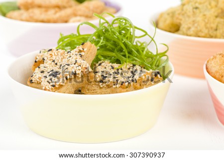 Sesame Prawn Toast - Star shaped shrimp toast in a bowl on a white background. Other party food on background.