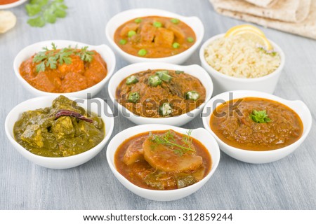 Vegetarian Curries - Selection of South Asian vegetarian curries in white bowls. Paneer Makhani, Palak Paneer, Aloo Matar, Baigan Bharta, Chilli Potatoes and Bhindi Masala, Pilau Rice and Chapattis.