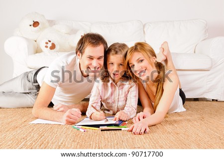Mother, father and daughter having fun at home. Doing homeworks and drawings