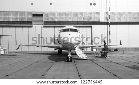 white private jet and open ladder at the airport on a background cloudy sky