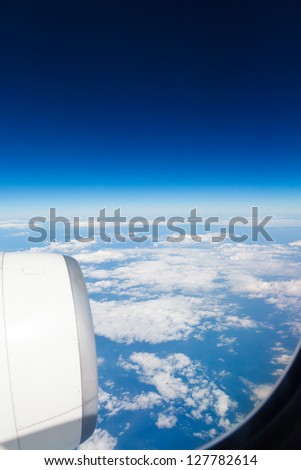 top view from the airplane on the blue sky and clouds and aircraft engine