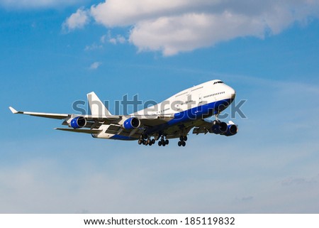 going to land a white passenger jet with landing gear on the background of blue sky, view from below