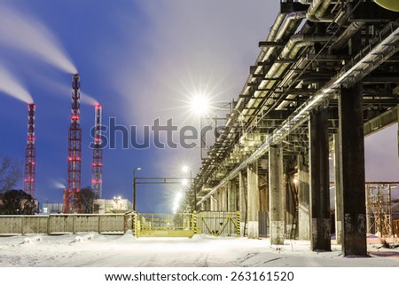 many pipes and smokestacks with industrial tower of metal on the chemical industry at night
