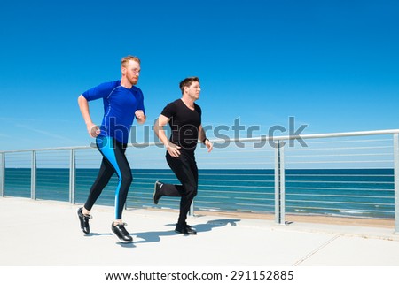 Two men running or jogging at a beachside park.