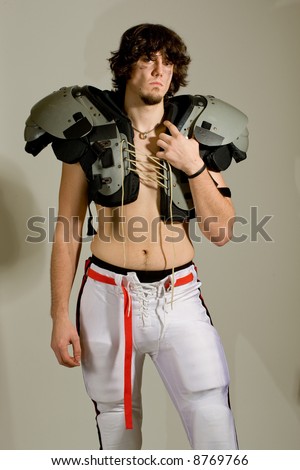 An American football player. Shirtless with shoulder pads.