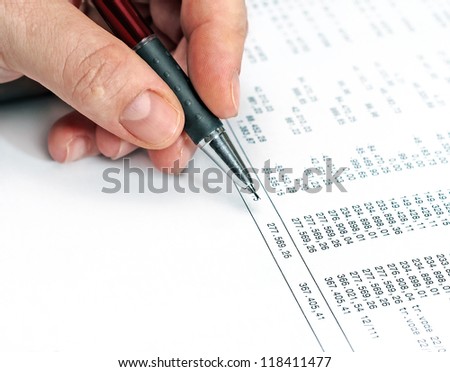 Human hand holds graphite pen over a balance statement sheet. Close up studio shot