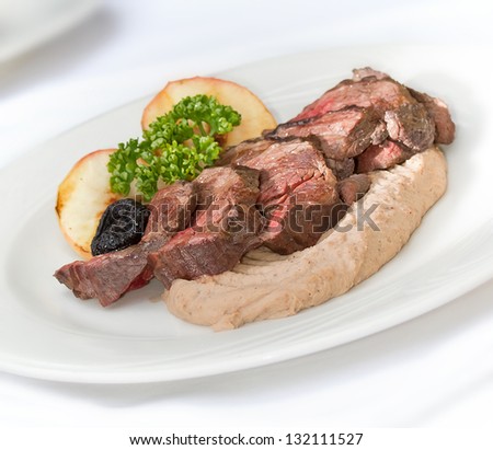 Venison steak cuts on a chestnut puree with dried plums and grilled apple slices