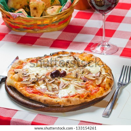 Mini pizza shot on a restaurant table with bread basket and red wine glass