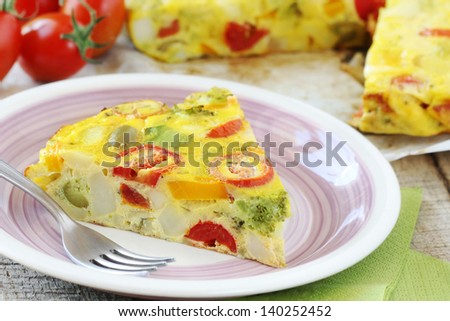 Slice of Spanish tortilla or omelette with potatoes, cherry tomatoes, bell pepper and broccoli on a plate