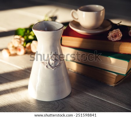 Bouquet of beautiful roses with a cup on the books in vintage style
