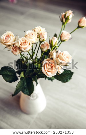 Beautiful bouquet of peach roses in vintage vase on a black background. Flowers