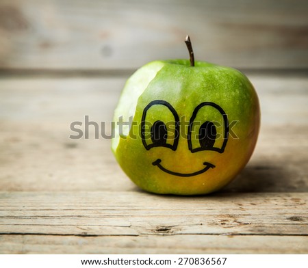 green apple with a hole bitten into it on a brown wooden surface