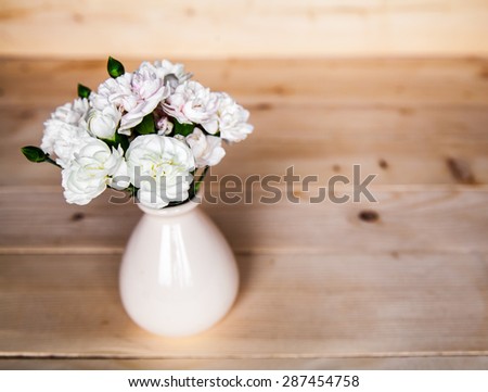 delicate bouquet of carnations in vintage vase with heart on wooden background. Valentine\'s Day