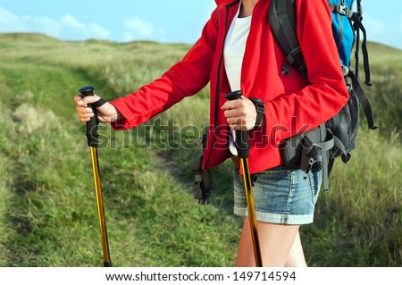 Close up of hiking young woman with backpack and trekking poles on the mountain trail