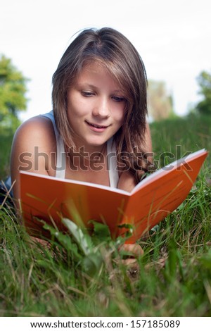 Portrait of a thoughtful teenage girl reading book in the park