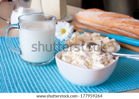 Dairy products: cottage cheese, milk and bulgarian cheese, and bread on blue towel on white wooden table