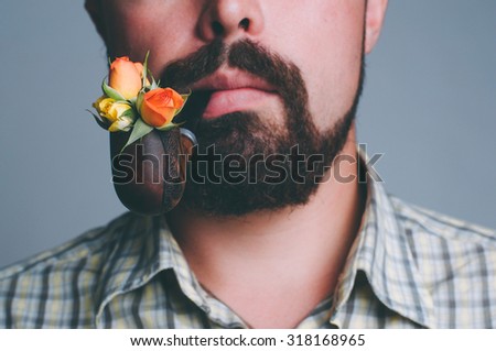 Portrait of man with beard and smoke pipe with rose flowers inside it, focus on flowers