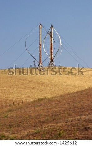 A trio of Darrieus type vertical axis wind turbines rusting in Northern California\'s pasture land.