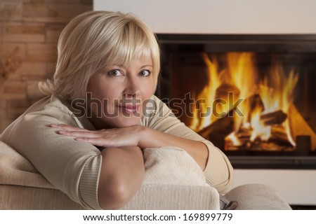 Portrait of beautiful adult woman sitting beside the fireplace