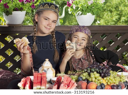 Two little girls dressed in Central Asian clothes have breakfast at chaikhana