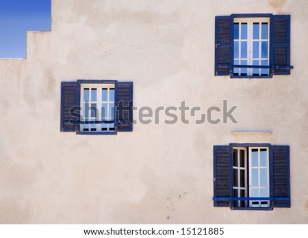 White wall with three blue windows of a colonial style