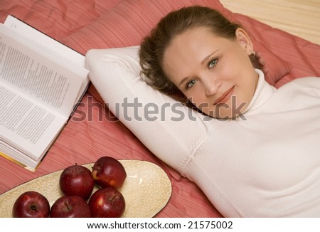 Attractive young adult Caucasian blond woman with apples and book.