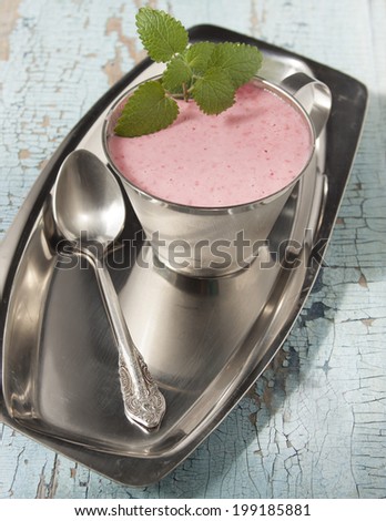 Cocktail of frozen raspberries with yogurt in a metal cup on a metal tray.