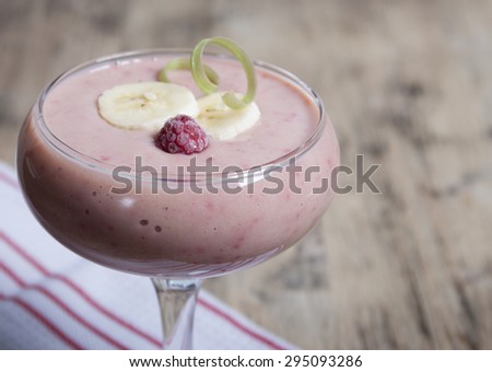 Smoothie of banana, frozen raspberries and rhubarb with yogurt in a glass.