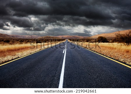 Open tar road with dark clouds