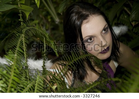 Beautiful brunette evil fairy in bush looking to the right of camera