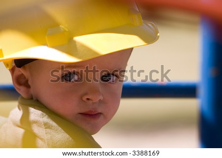 Young child with beautiful blue eyes wearing a yellow hard hat