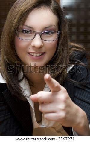 Attractive brunette business woman wearing business suit pointing at camera