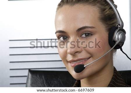 Young blond call center agent talking on the headset in a modern office setting