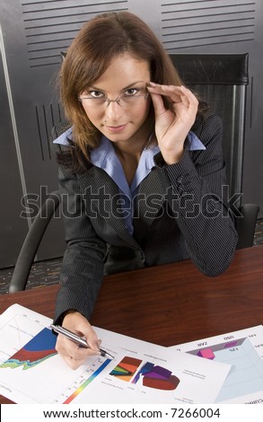 Young attractive businesswoman looking at graphs in a modern office setting
