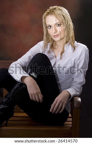 Curly blond with tight pants wearing black boots sitting in chair with wet hair