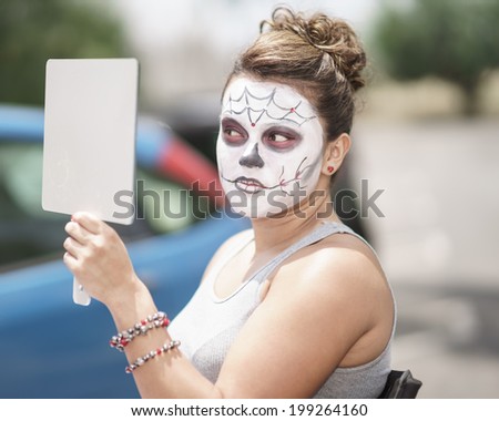 Female Day of The Dead model in skeleton make up looking in the mirror