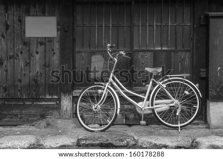 old bicycle leaning against japanese style house in black and white