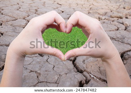background of hand in heart shape with green field inside on the crack earth