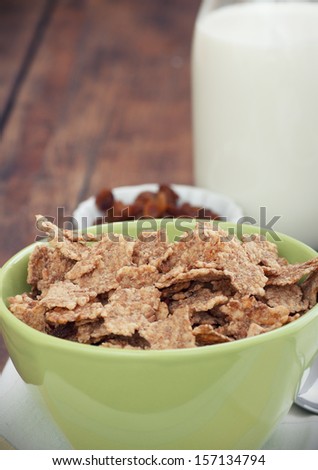 A bowl of cereal with almonds, milk and dried grapes