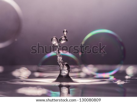 A macro shot of a water drop collision amongst some soap bubbles.