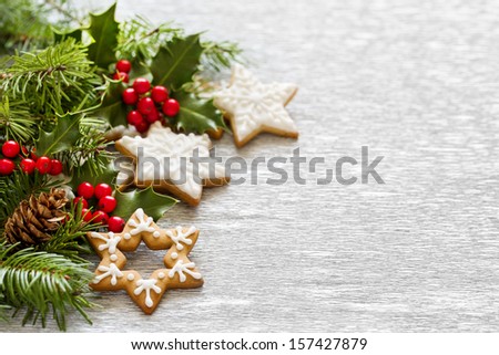 Christmas Silver background with holly branch, berries, firtree and gingerbread cookies.