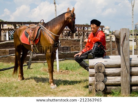 TAMAN, RUSSIA - JUNE 14: Cossack led to the watering his horse and sat down to rest on the well on June 14, 2011 in Taman.
